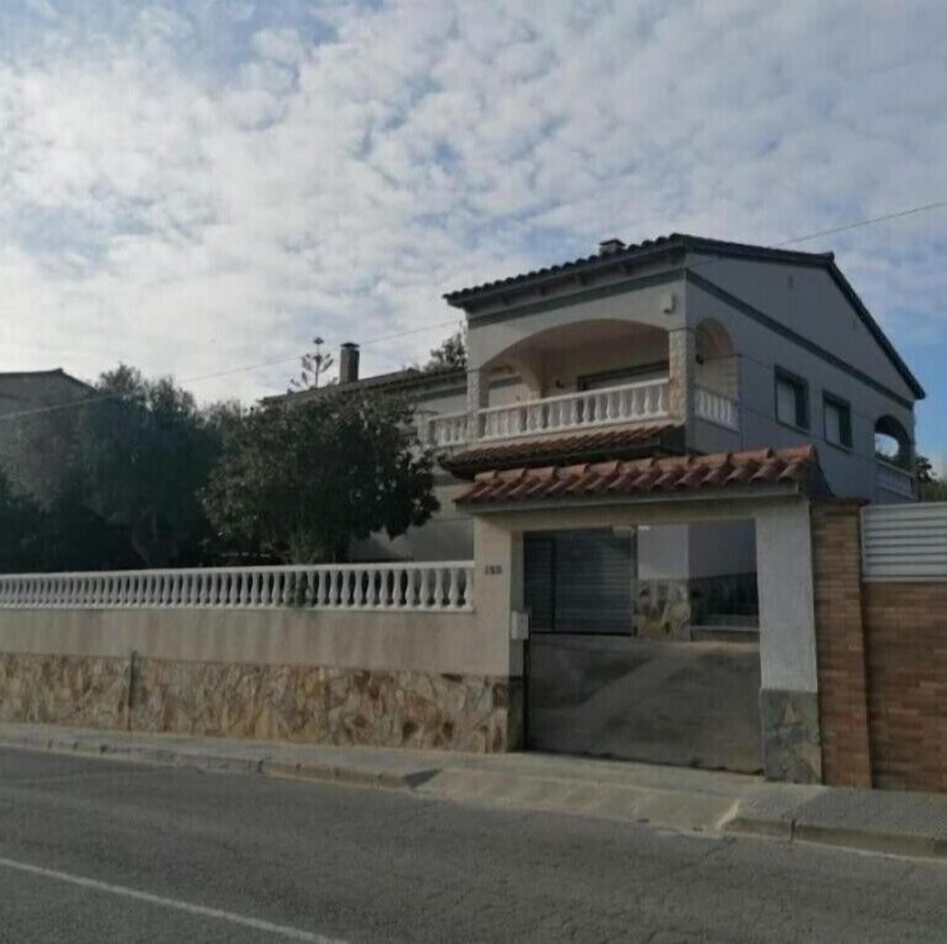 A two-story building with a balcony, a garage, and a gated entrance.