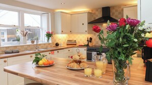 Une cuisine moderne avec un plan de travail en bois, un évier et une cuisinière. Un vase rempli de fleurs est posé sur le plan de travail.