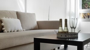 Una sala de estar con un sofá, una mesa de centro y una bandeja decorativa con botellas y vasos.