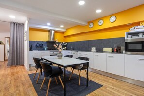 A modern kitchen with white cabinets, a dining table with chairs, a microwave, and a coffee maker.