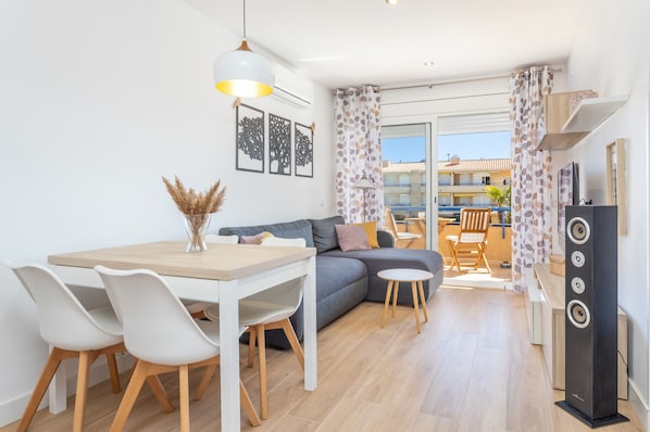 Un salon moderne comprenant une table à manger, des chaises, un canapé, un téléviseur et un balcon avec vue.