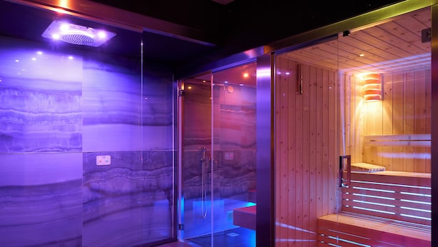 A modern spa room with a glass enclosure, a wooden sauna, and a marble wall. - Le Maginot Relais (Monticelli d'Ongina)
