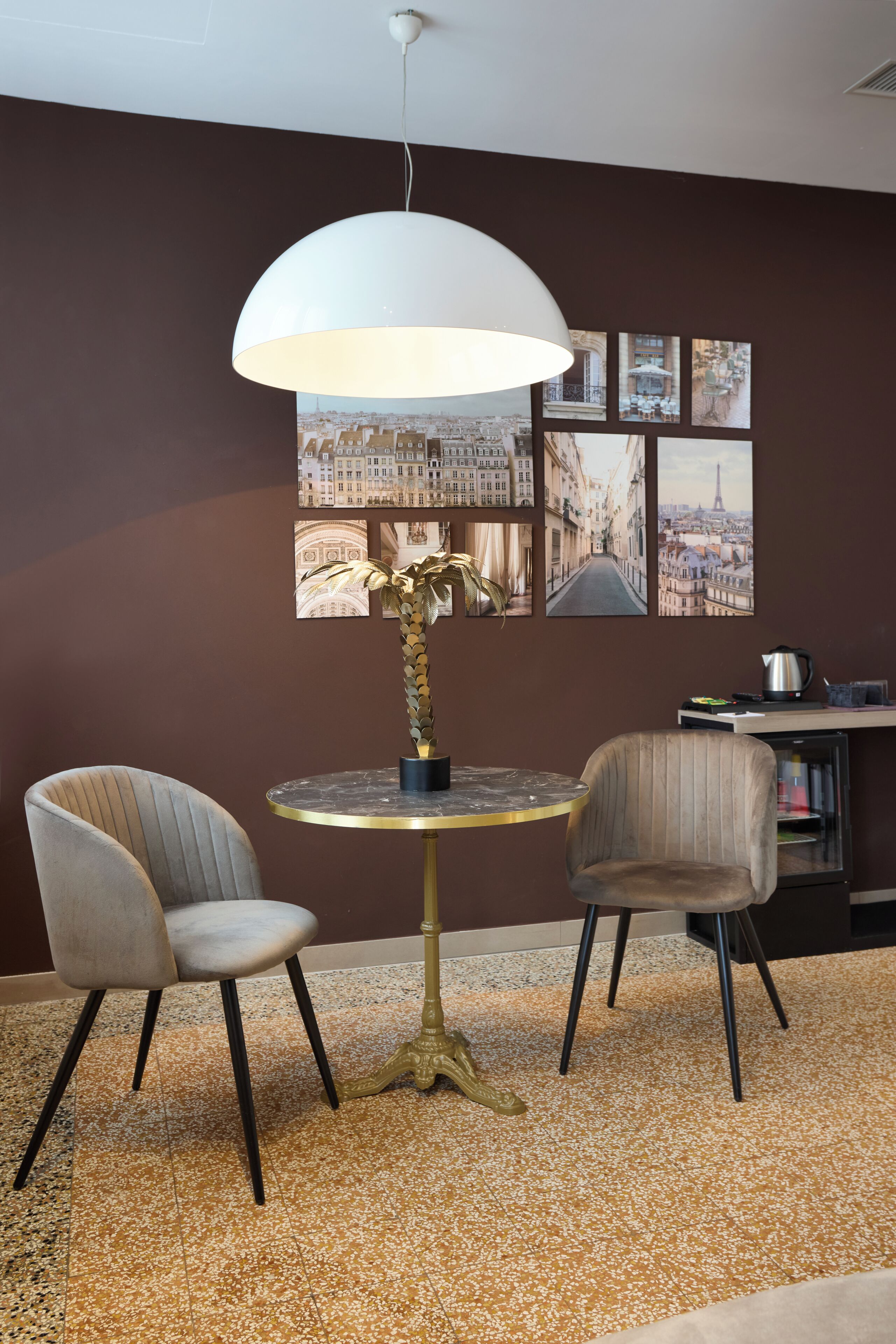 Una habitación con una mesa redonda, dos sillas, una lámpara de pie y una pared decorada con cuadros.