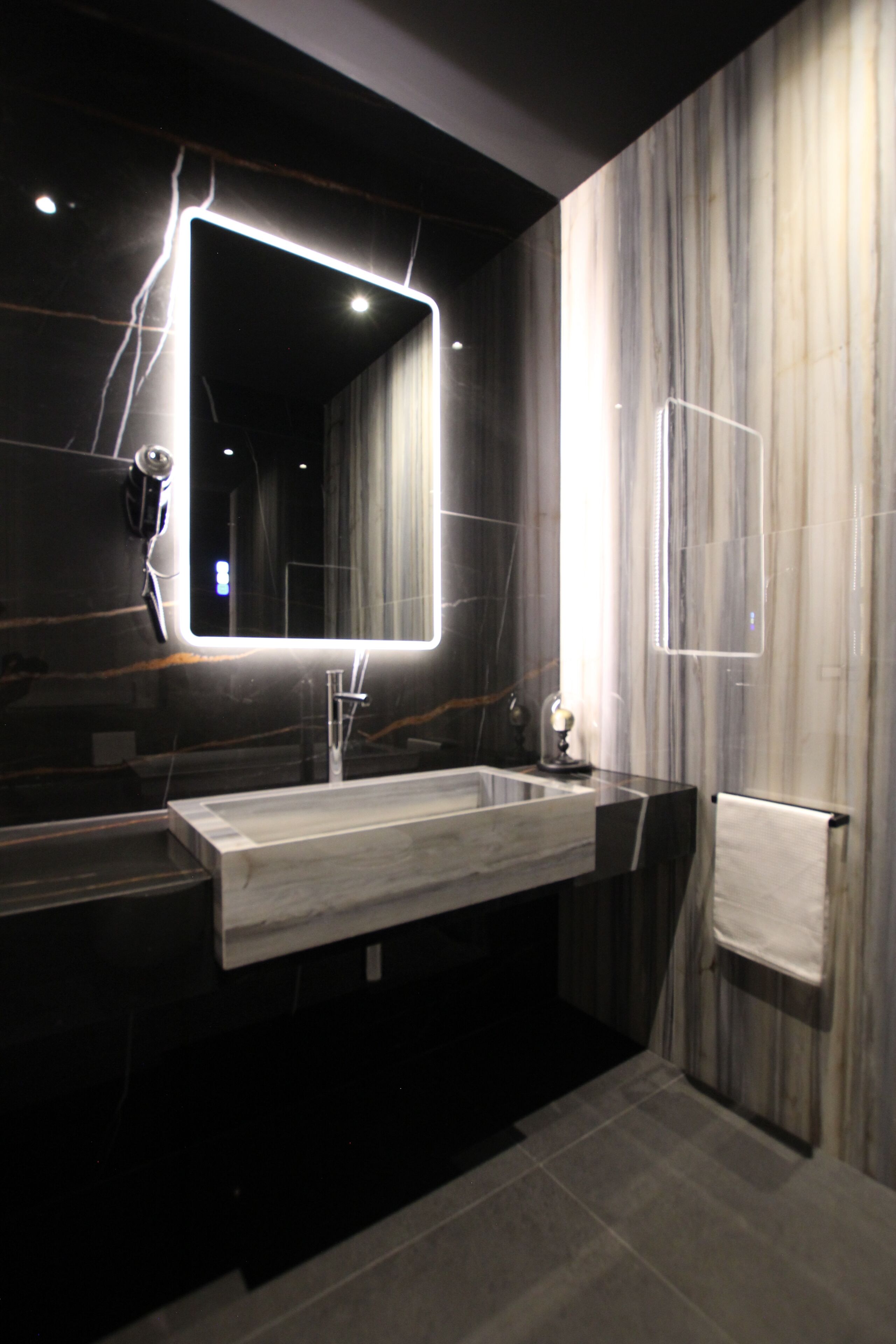 A modern bathroom with a large mirror, a sink, and a towel rack.