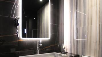 A modern bathroom with a large mirror, a sink, and a towel rack.