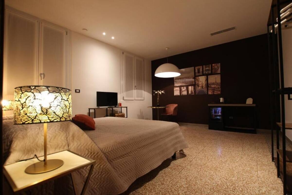 Ein Schlafzimmer mit Bett, Nachttisch, Lampe, Schreibtisch, Stuhl und Wandbild.