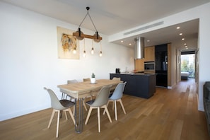 A modern kitchen with a wooden dining table, grey chairs, and a hanging light fixture. - Luxury Acropolis Rooftop Apartment (Athens)