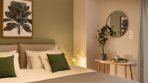 A neatly made bed with green and white pillows, a bedside table with a lamp, and a framed botanical print on the wall. - Marina Zeas Apartment by the sea (Piraeus)