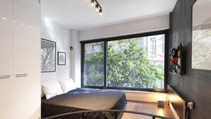 A modern bedroom with a large window, a bed, a black metal railing, and a view of greenery outside. - 200mb Fibre Remote Workers' Dreamhouse (Athens)