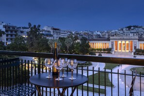 Een balkon met een tafel voor vier personen, met uitzicht op een stadsgezicht in de schemering.