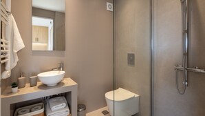 A modern bathroom with a glass-enclosed shower, a white sink, and a toilet. - Stunning Acropolis View Apartment (Athens)