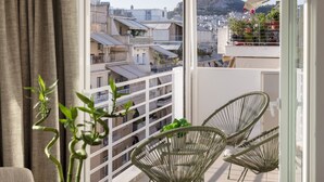 A balcony with a table, chairs, and a vase of plants. - Stunning Acropolis View Apartment (Athens)