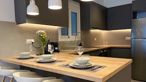 A modern kitchen with a central island, bar stools, pendant lighting, and a built-in oven. - Nea Smirni Square Chic Apartment (Nea Smirni)