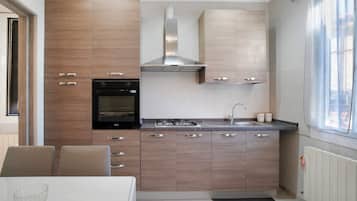 Une cuisine moderne avec des meubles en bois, un four encastré, une cuisinière à gaz et une hotte en acier inoxydable.