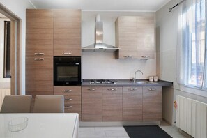 A modern kitchen with wooden cabinets, a built-in oven, a gas stove, and a stainless steel range hood.