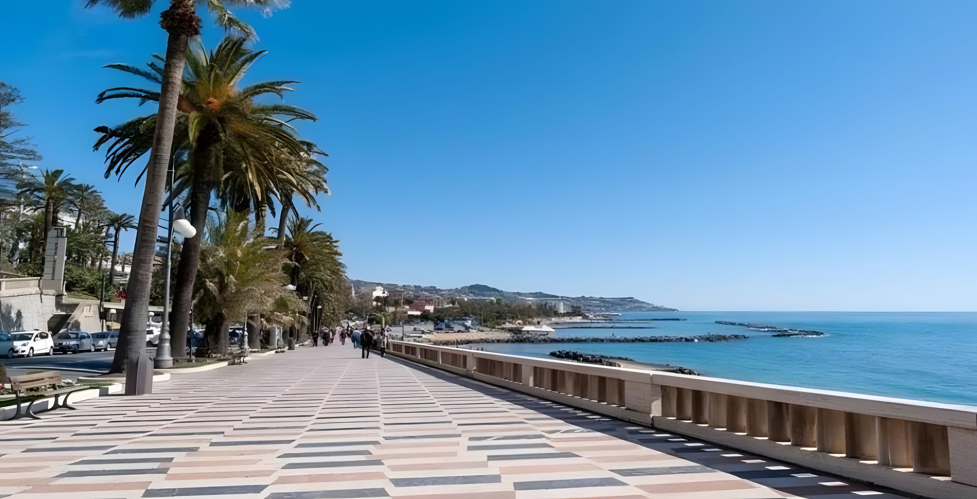 Ein gepflasterter Weg mit Palmen, einem Geländer und Blick auf das Meer.