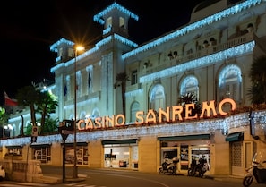 Een gebouw met verlichte borden waarop 'CASINO SANREMO' staat en een grote, gebogen ingang.