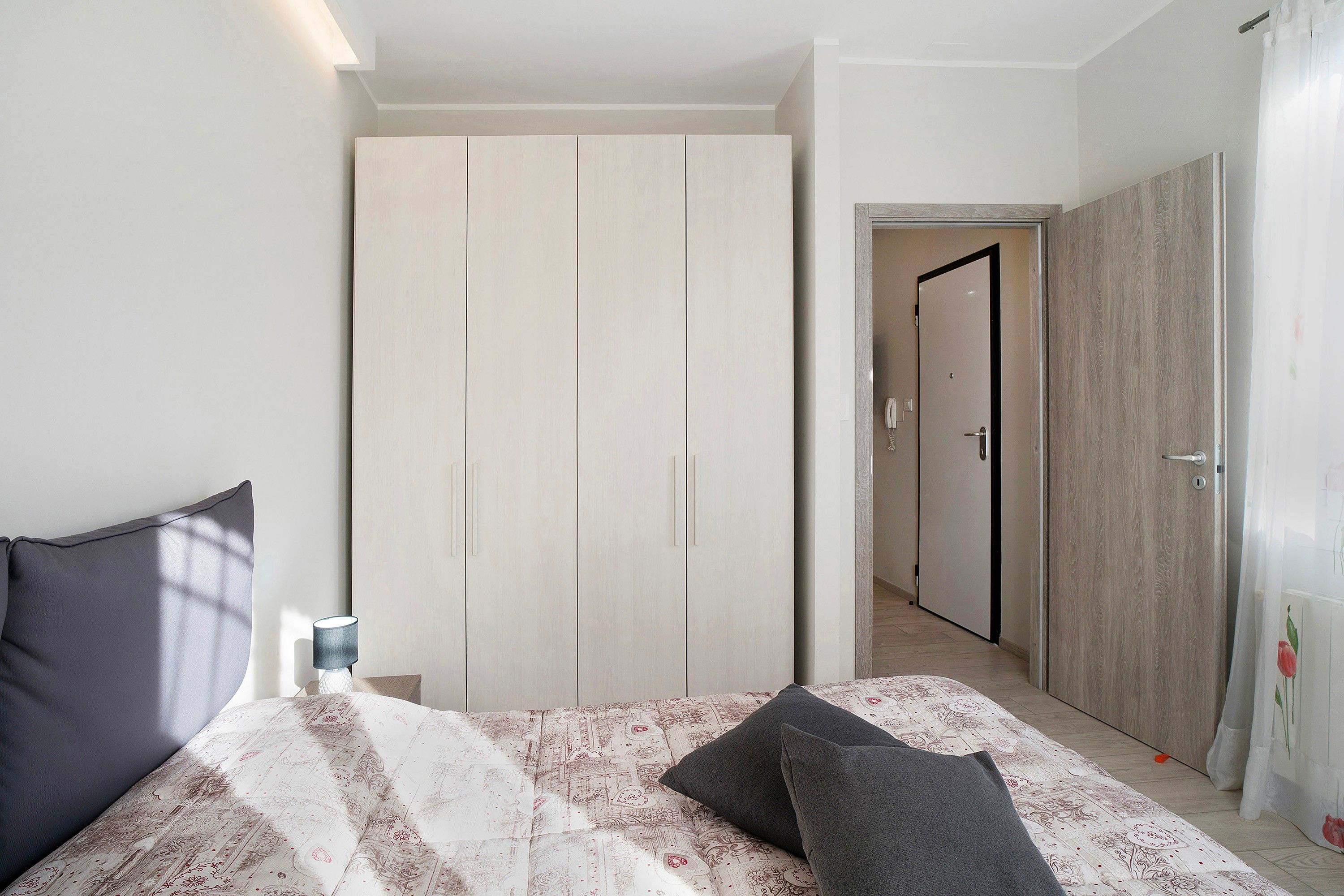 Une chambre à coucher comprenant un lit, une armoire et une porte donnant sur une autre pièce.