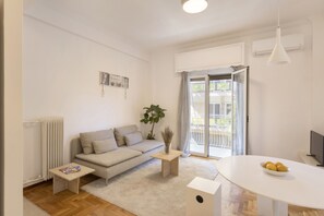 Uma sala de estar moderna com sofá, mesa de centro e mesa de jantar com frutas.