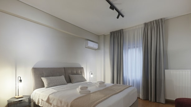 A modern bedroom with a large bed, a bedside table, a lamp, and a radiator. - Urban Luxury in the Heart of Athens (Athens)