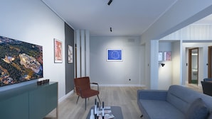 A modern living room with a large painting, a sofa, a chair, and a coffee table. - Urban Luxury in the Heart of Athens (Athens)