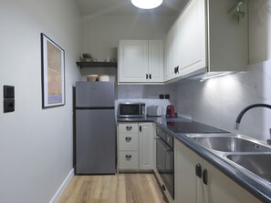 A compact kitchen with white cabinets, a stainless steel refrigerator, a microwave, a toaster, and a sink. - Urban Luxury in the Heart of Athens (Athens)