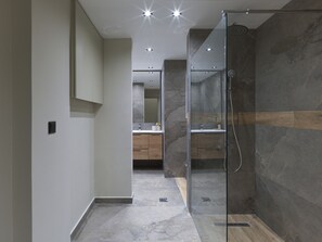 A modern bathroom with a glass-enclosed shower, marble flooring, and a visible sink area with wooden cabinets. - Urban Luxury in the Heart of Athens (Athens)