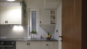 A modern kitchen with white cabinets, a stainless steel sink, and a built-in oven. - Urban Luxury in the Heart of Athens (Athens)