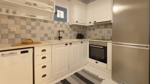 Una cocina moderna con armarios blancos, un refrigerador de acero inoxidable, un horno empotrado y una cafetera.