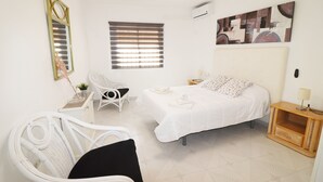 Ein Schlafzimmer mit einem Bett, einem Sessel, einem kleinen Tisch und einem Bild an der Wand.