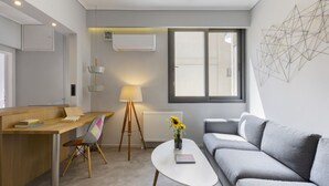 Ein modernes Wohnzimmer mit einem grauen Sofa, einem Holztisch, einem weißen Couchtisch und einer Stehlampe.