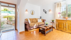 A living room with a sofa, a coffee table, a cabinet, and a door leading to a balcony. - Apartment 'Sillero Dos' with Shared Pool, Private Terrace and Air Conditioning (Moraira)