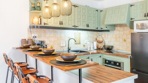 A kitchen with a wooden island, green cabinets, and a stainless steel refrigerator. - Apartment 'Sillero Dos' with Shared Pool, Private Terrace and Air Conditioning (Moraira)