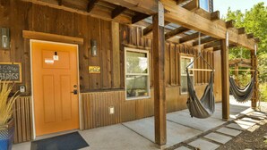 A wooden cabin with a wooden door, a window, and a hammock hanging under a wooden beam. - Moab Digs #1 - Your Downtown Basecamp! (Moab)