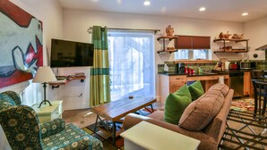 A compact living space with a sofa, a table, a TV, and a kitchen area with a microwave and shelves. - Moab Digs #1 - Your Downtown Basecamp! (Moab)