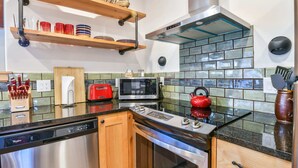 A modern kitchen with stainless steel appliances, wooden shelves, and a tiled backsplash. - Moab Digs #1 - Your Downtown Basecamp! (Moab)