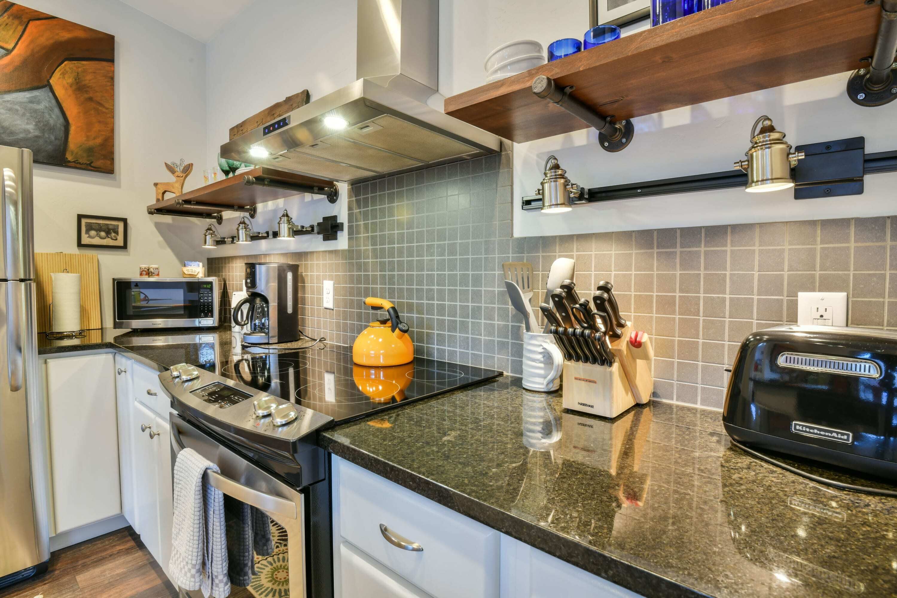 Una cocina moderna con electrodomésticos de acero inoxidable, una encimera negra y un horno empotrado.