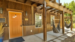 A wooden cabin with a wooden door, a window, and a hammock hanging under a wooden beam. - Moab Digs #2 - Your Downtown Basecamp! (Moab)