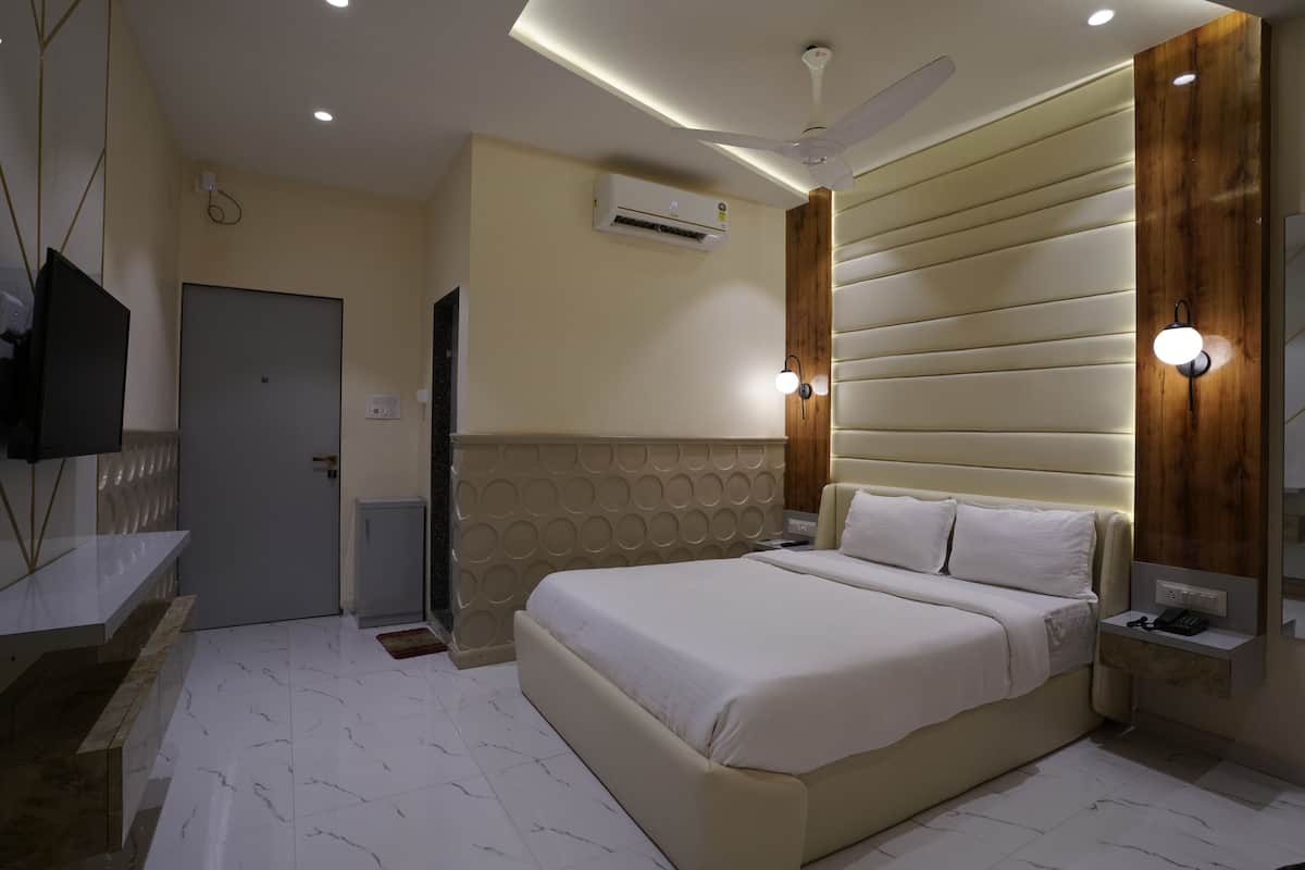 A modern bedroom with a large bed, a TV, an air conditioner, and a ceiling fan.