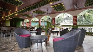 Un espace patio intérieur aménagé avec des meubles en osier, des ventilateurs de plafond et un sol carrelé.