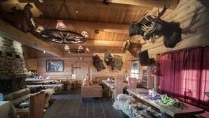 Ein rustikales Interieur mit Holzwänden, einem Steinofen und an den Wänden angebrachten Geweihen.
