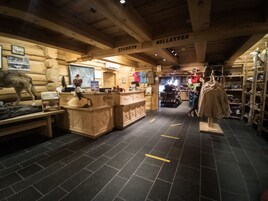 A wooden interior with a ticket counter, a reception area, and a clothing display.