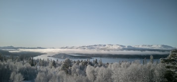 A mountainous landscape with snow-covered peaks and a lake in the foreground.