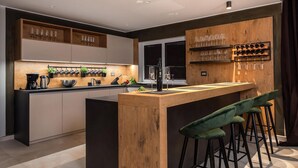 Une cuisine moderne dotée d’un îlot central, de tabourets de bar et de supports à bouteilles de vin.