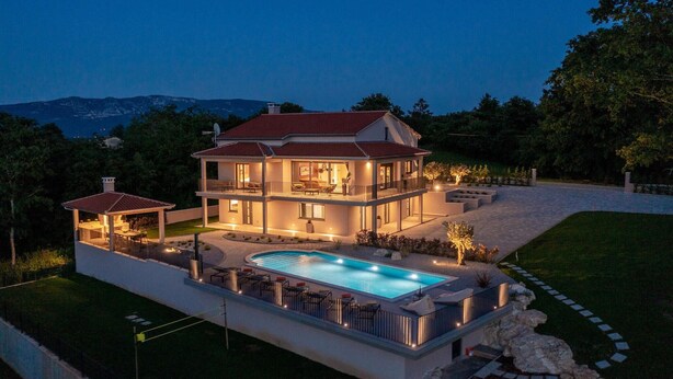 Une maison à deux étages avec une piscine, un patio couvert et un jardin aménagé.