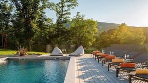 Un espace aménagé au bord de la piscine, avec des chaises longues, une petite piscine et une terrasse.
