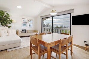 Una sala de estar moderna con una mesa de comedor, sofá y ventanas amplias.