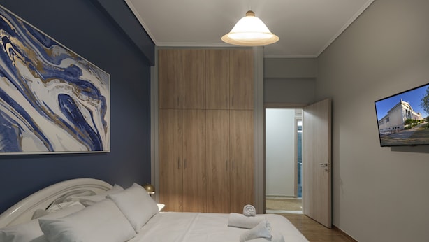 Une chambre à coucher avec un lit, un grand tableau, une armoire et un téléviseur.