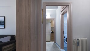 Un couloir menant à une cuisine équipée d’un lave-linge et d’un radiateur.