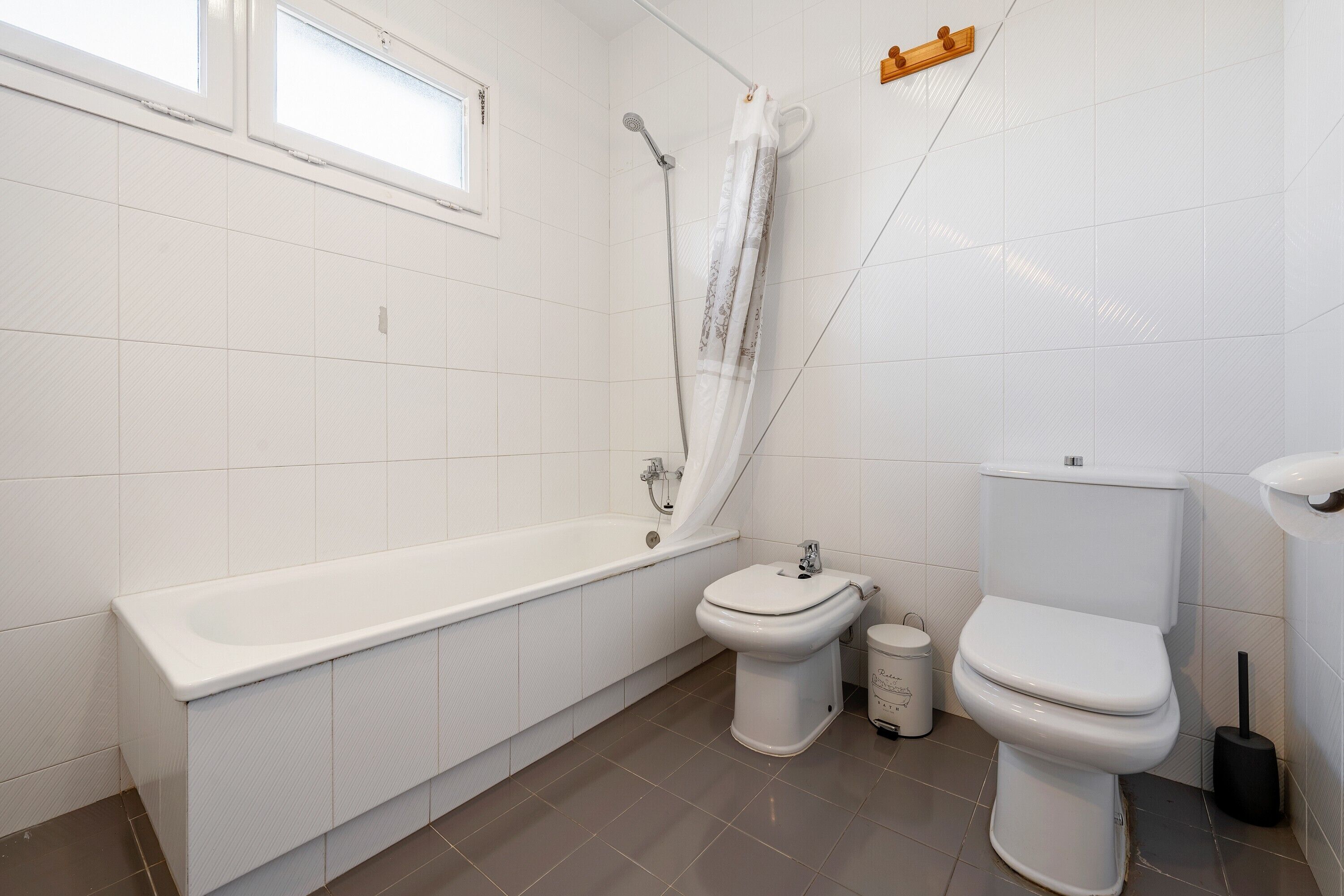 A bathroom with a bathtub, toilet, and shower curtain.